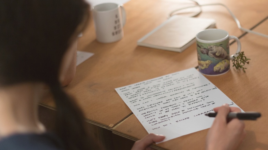 person taking notes with a pen on a table